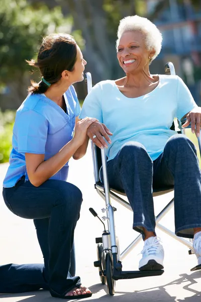 Aide Pousser une femme âgée en fauteuil roulant — Photo