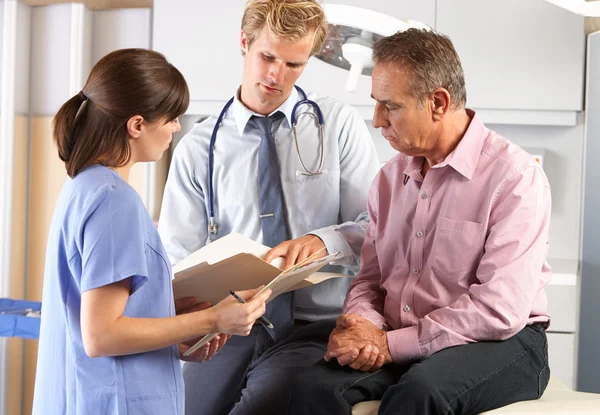 Paciente masculino siendo examinado por médico y pasante —  Fotos de Stock