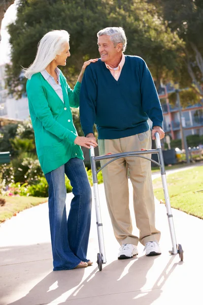 Mujer mayor ayudando a su marido con el marco de caminar —  Fotos de Stock