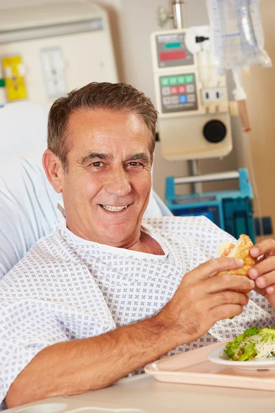 Paciente masculino disfrutando de la comida en la cama del hospital —  Fotos de Stock