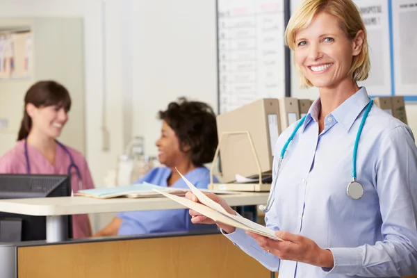 Vrouwelijke arts lezen van patiënt notities op verpleegkundigen station — Stockfoto