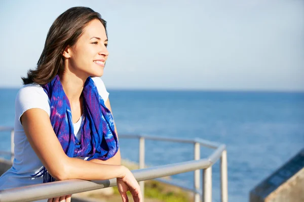 Hispánský žena dívá přes zábradlí na moři — Stock fotografie