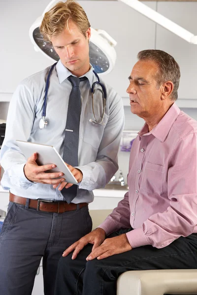 Доктор обсуждает записи с пациентом с помощью цифрового планшета — стоковое фото
