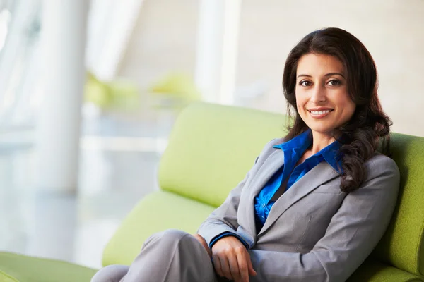 Portret van zakenvrouw zittend op bank in modern kantoor — Stockfoto