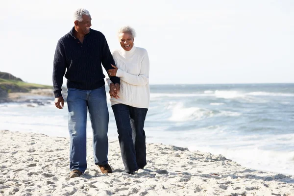 Coppia anziana a piedi lungo la spiaggia insieme Foto Stock