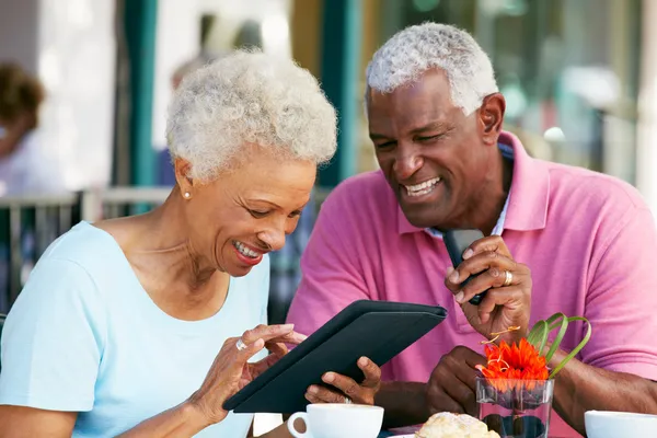 Seniorenpaar nutzt Tablet-Computer im Outdoor-Café Stockbild