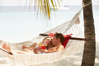 Romantic Couple Relaxing In Beach Hammock clipart