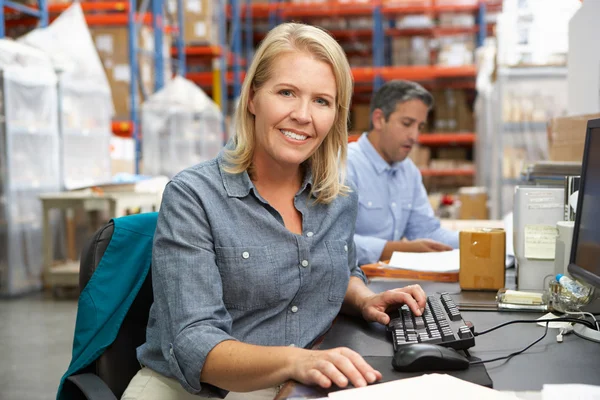 Empresária trabalhando na mesa no armazém — Fotografia de Stock