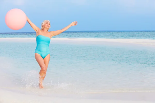 Mujer mayor salpicando en hermoso mar celebración globo —  Fotos de Stock
