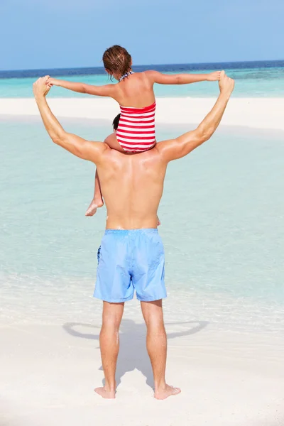 ビーチでの休暇に娘を運んで父の背面図 — ストック写真