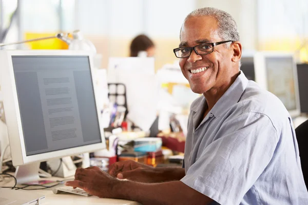 Hombre trabajando en el escritorio en la oficina creativa ocupada — Foto de Stock