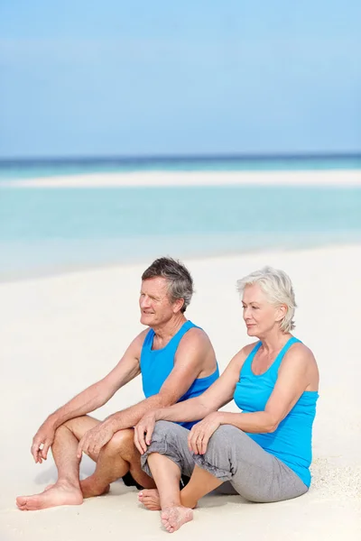 Casal sênior em roupas esportivas relaxante na bela praia — Fotografia de Stock