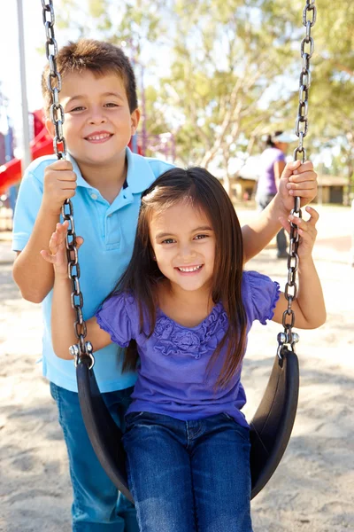 Jongen en meisje spelen op de schommel in park — Stockfoto