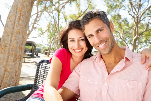 Романтическая пара, сидящая вместе на скамейке в парке — стоковое фото