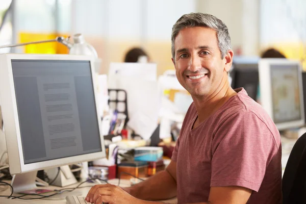 Mann arbeitet am Schreibtisch im geschäftigen Kreativbüro — Stockfoto