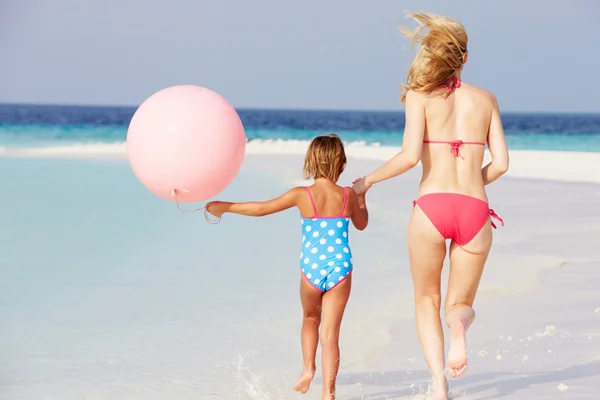 Mãe e filha correndo em bela praia com balão — Fotografia de Stock