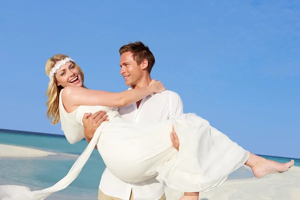 Bräutigam trägt Braut bei schöner Strandhochzeit — Stockfoto