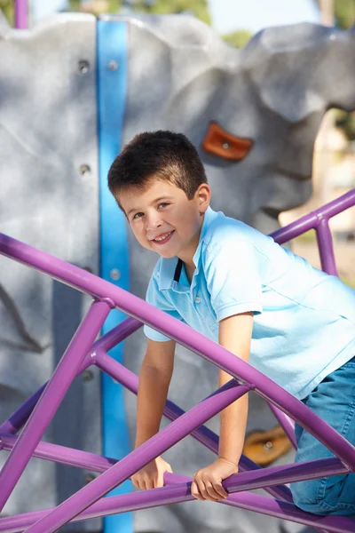 Ragazzo su arrampicata telaio in parco — Foto Stock