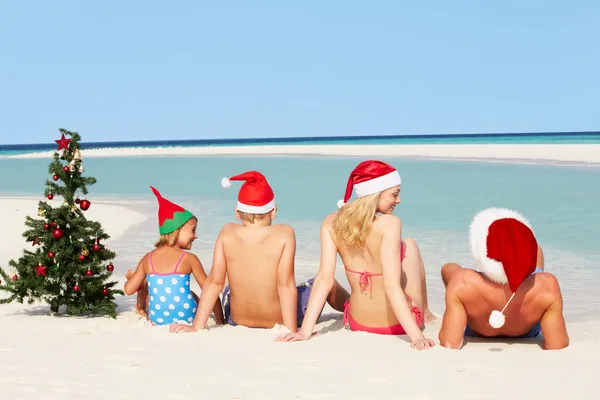 Família sentada na praia com árvore de Natal e chapéus — Fotografia de Stock
