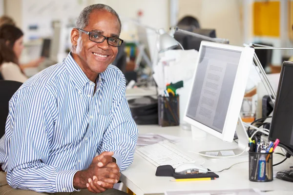 Hombre trabajando en el escritorio en la oficina creativa ocupada — Foto de Stock