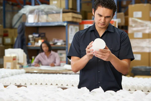 Trabajador de fábrica que comprueba mercancías en línea de producción — Foto de Stock