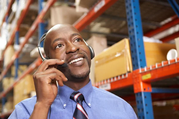 Homem de negócios usando fone de ouvido no armazém de distribuição — Fotografia de Stock