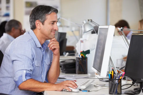 Hombre trabajando en el escritorio en la oficina creativa ocupada — Foto de Stock