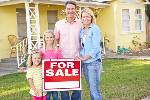 Familie staande door voor verkoop teken buiten huis — Stockfoto