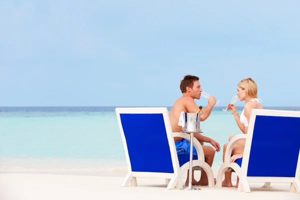 Ζευγάρι στην παραλία χαλαρώνοντας σε καρέκλες και πίνοντας σαμπάνια — Φωτογραφία Αρχείου
