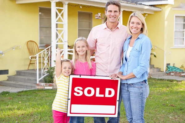 Família em pé pelo sinal vendido fora de casa — Fotografia de Stock