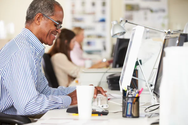 Man arbetar vid skrivbordet i upptagen Creative Office — Stockfoto