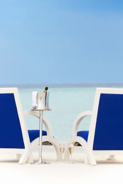 Μπουκάλι σαμπάνια μεταξύ καρέκλες στην όμορφη παραλία — Φωτογραφία Αρχείου