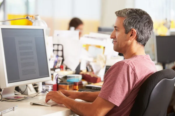 Hombre trabajando en el escritorio en la oficina creativa ocupada — Foto de Stock