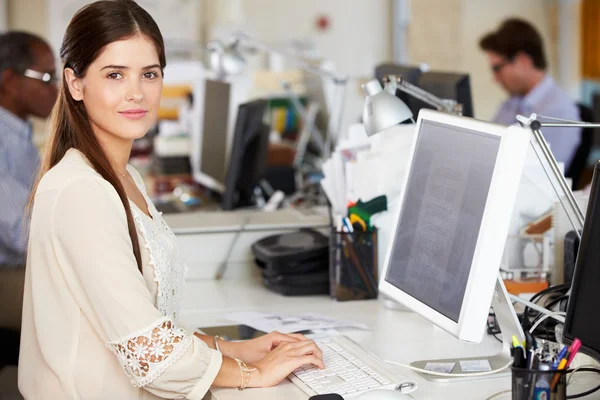 Kvinna som arbetar på skrivbord i upptagen kreativa kontor — Stockfoto