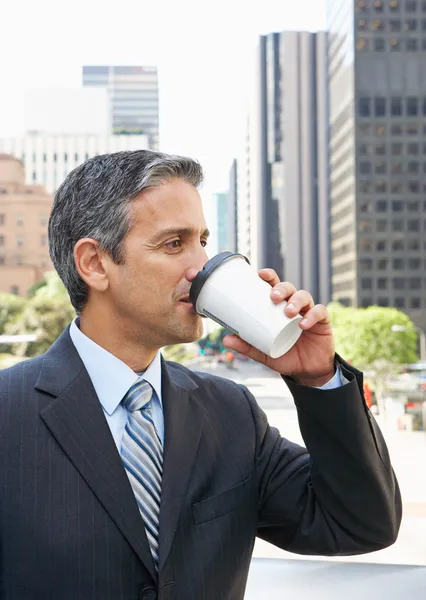 Geschäftsmann trinkt Kaffee zum Mitnehmen vor dem Büro — Stockfoto