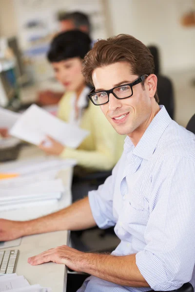 Hombre trabajando en el escritorio en la oficina creativa ocupada — Foto de Stock