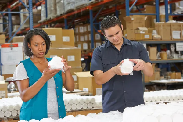 Trabalhadores da fábrica verificando bens na linha de produção — Fotografia de Stock