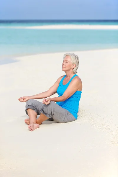 Seniorin meditiert am schönen Strand — Stockfoto