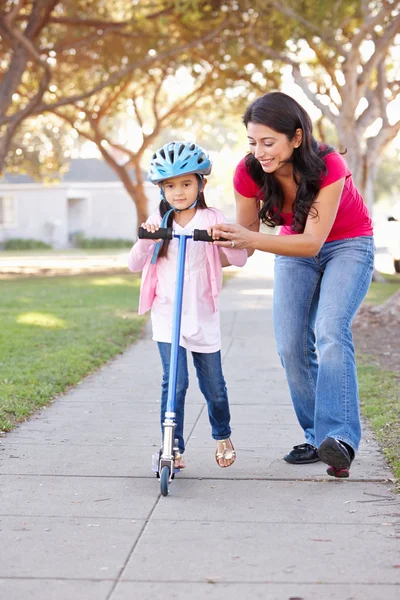 Madre enseñando hija a montar scooter —  Fotos de Stock
