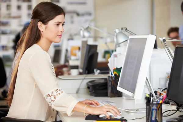 Kvinna som arbetar på skrivbord i upptagen kreativa kontor — Stockfoto
