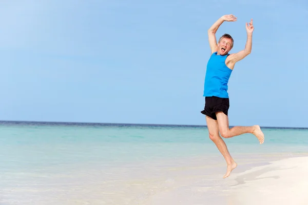 Äldre man hoppa på stranden — Stockfoto