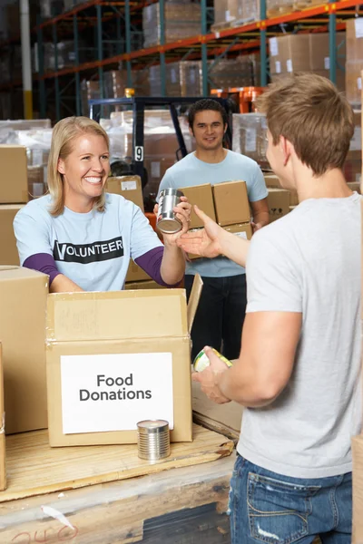 Vrijwilligers verzamelen voedsel donaties in magazijn — Stockfoto