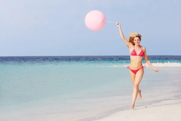 Donna in bikini che corre su una bella spiaggia con palloncino — Foto Stock