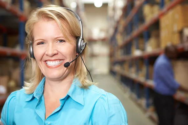 Zakenvrouw hoofdtelefoon met distributie magazijn — Stockfoto