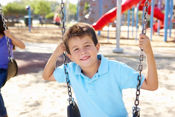 Ragazzo su swing in parco — Foto Stock