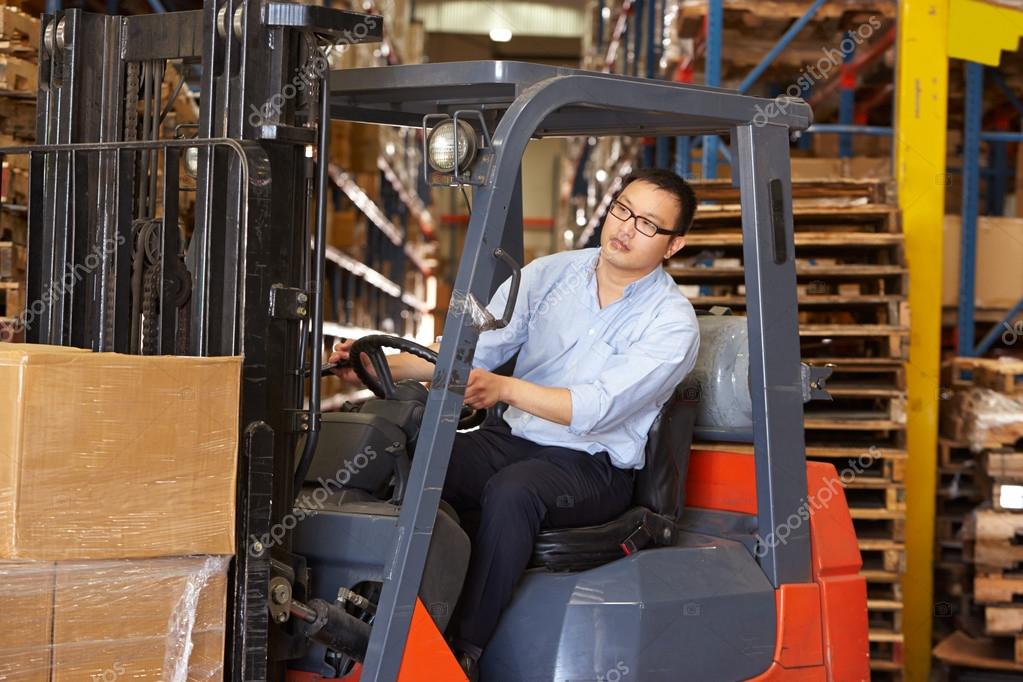 Man Driving Fork Lift Truck In Warehouse Stock Photo by ©monkeybusiness