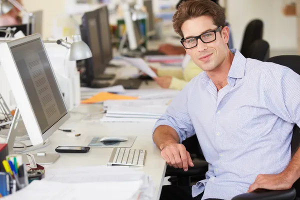 Hombre trabajando en el escritorio en la oficina creativa ocupada —  Fotos de Stock