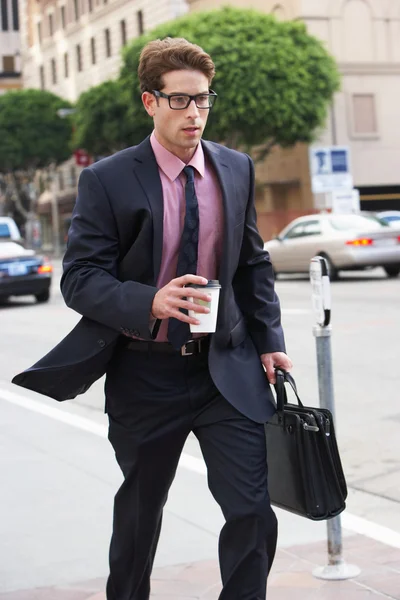 Empresario corriendo a lo largo de la calle sosteniendo el café para llevar —  Fotos de Stock