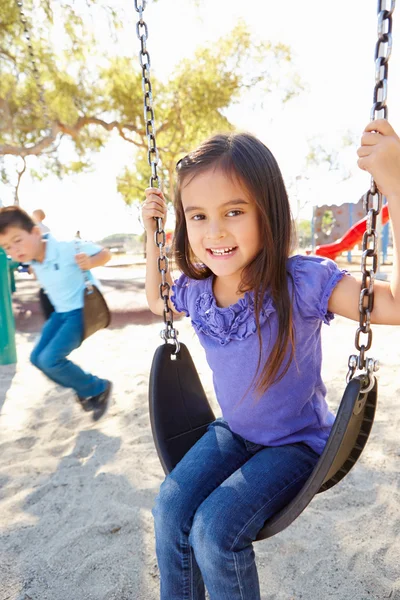 Chico y chica jugando en swing en parque — Foto de Stock