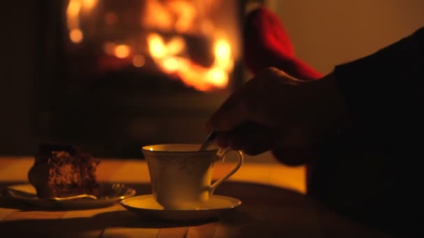 Man ontspant door warme vuur dan roert drank met een theelepel — Stockvideo